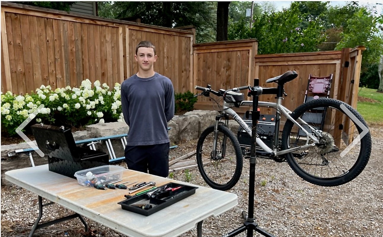 Asher standing at his bike repair workstation with tools